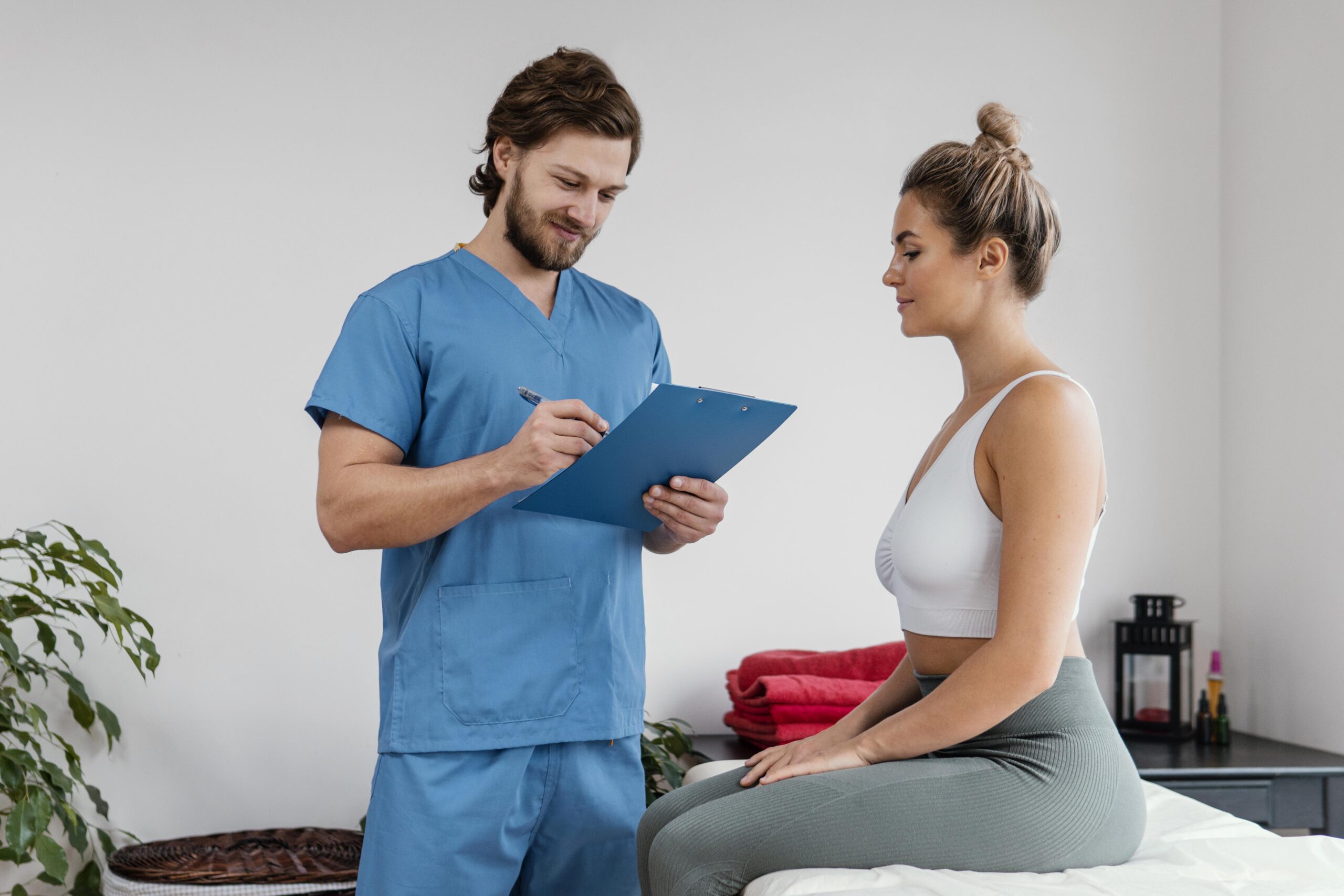 male-osteopathic-therapist-with-female-patient-signing-clipboard-clinic